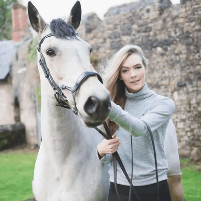 Equisport Equestrian Roll-Neck Jumper on model beside a horse in a countryside setting.